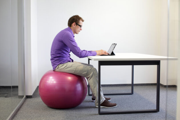 El fitball ayuda a combatir el sedentarismo Hombre trabajando en la computadora sentado en una pelota