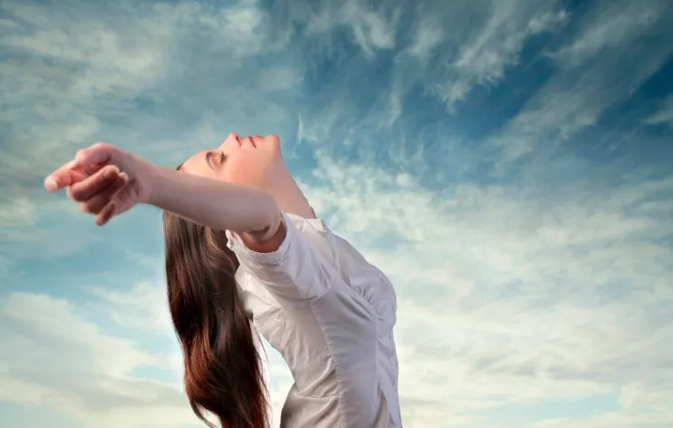 Mujer respirando profundamente al aire libre, un ejercicio de relajación para hacerle frente a la ansiedad y al pánico.