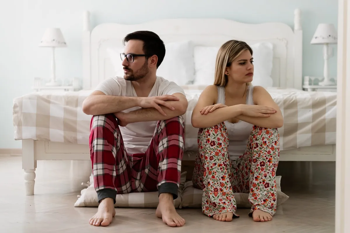 Pareja al borde de la cama mostrando problemas de comunicacion