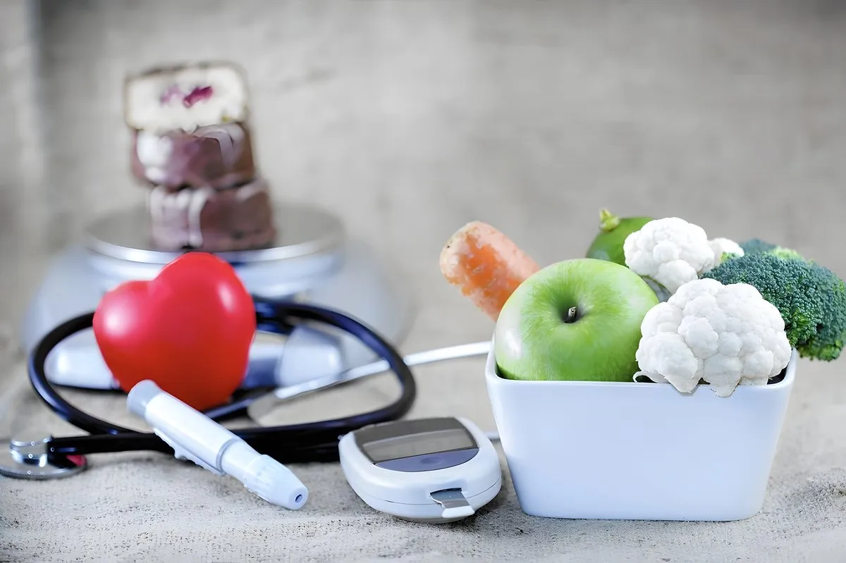 Frutas y verduras frescas junto a un glucómetro, un estetoscopio y un corazón de goma, representando el cuidado integral de la diabetes.