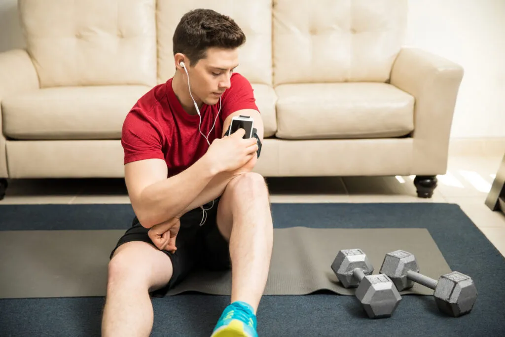 Hombre haciendo ejercicio en casa con auriculares, escuchando música motivadora en Spotify 2025.