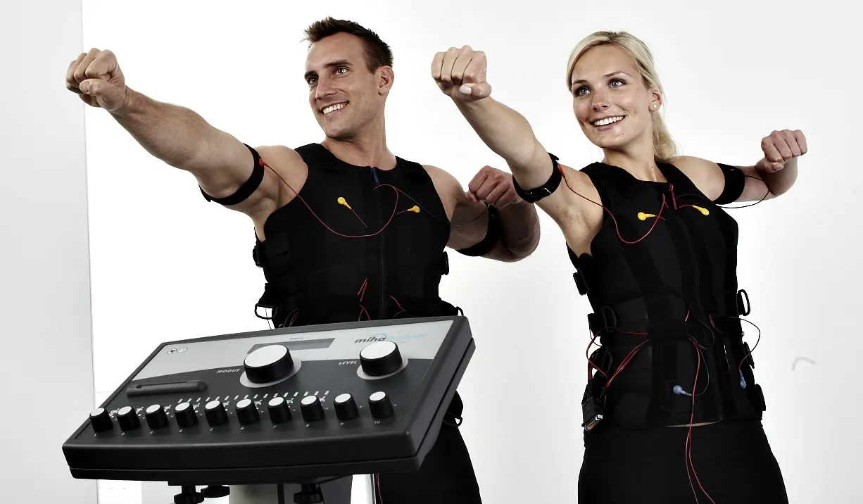 Pareja realizando un entrenamiento de electrofitness con trajes de electrodos para tonificar glúteos y abdomen.