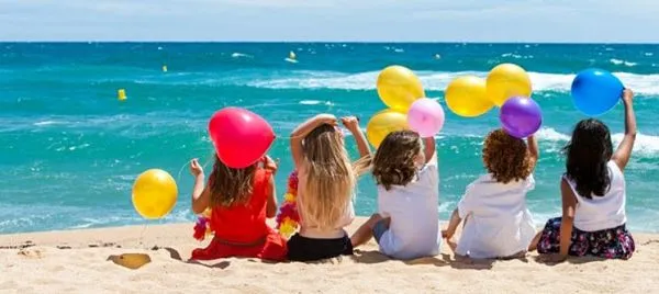 Grupo de niños en la playa con globos, simbolizando la realización de deseos en los sueños infantiles según el psicoanálisis.