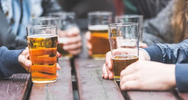 Grupo de amigos bebiendo alcohol socialmente, experimentando la energía y confianza que a menudo se asocia con las bebidas espirituosas.