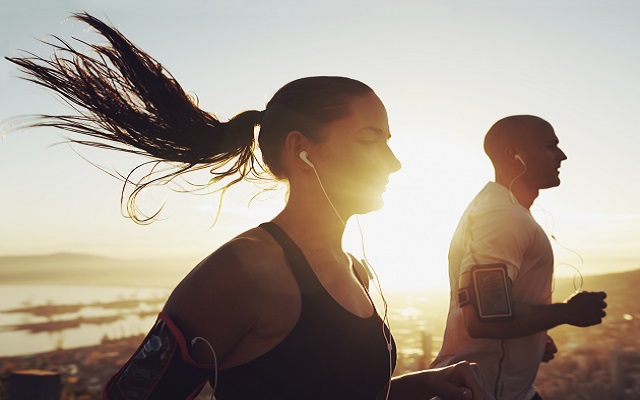 Música para entrenar en 2025: las mejores playlists de Spotify. Pareja corriendo al aire libre mientras escucha música con auriculares, motivados por una playlist de Spotify 2025.