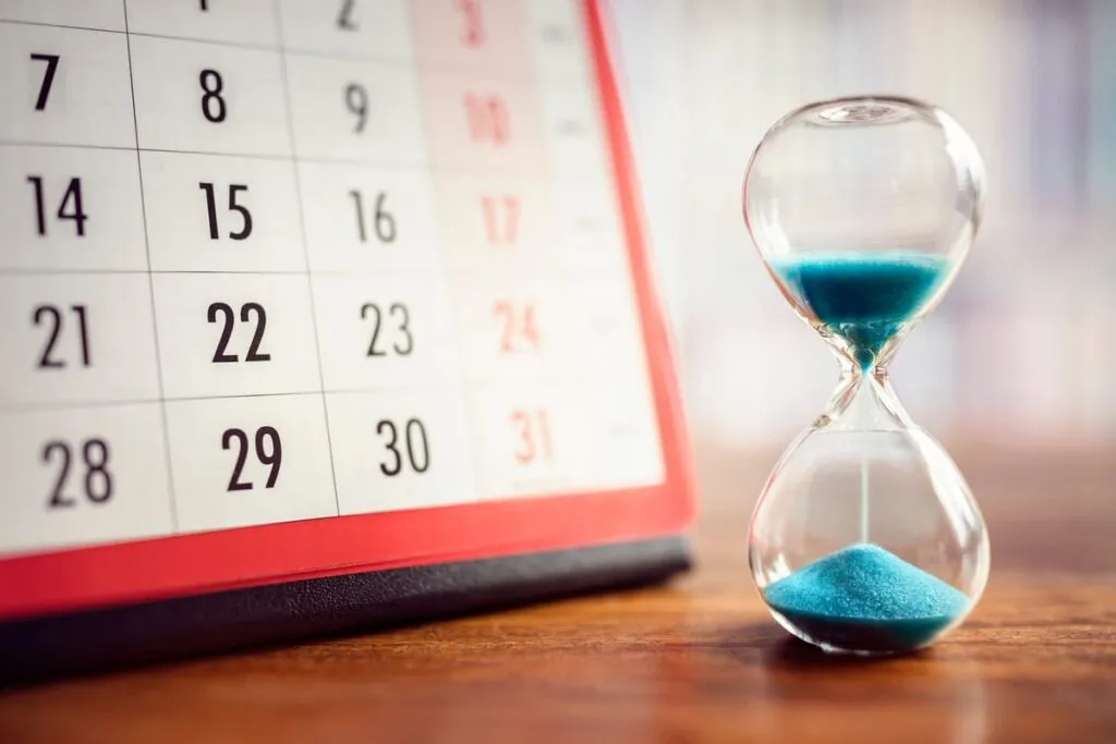 Reloj de arena y calendario simbolizando el paso del tiempo y cómo la mente elabora el dolor a través de un sueño reparador.