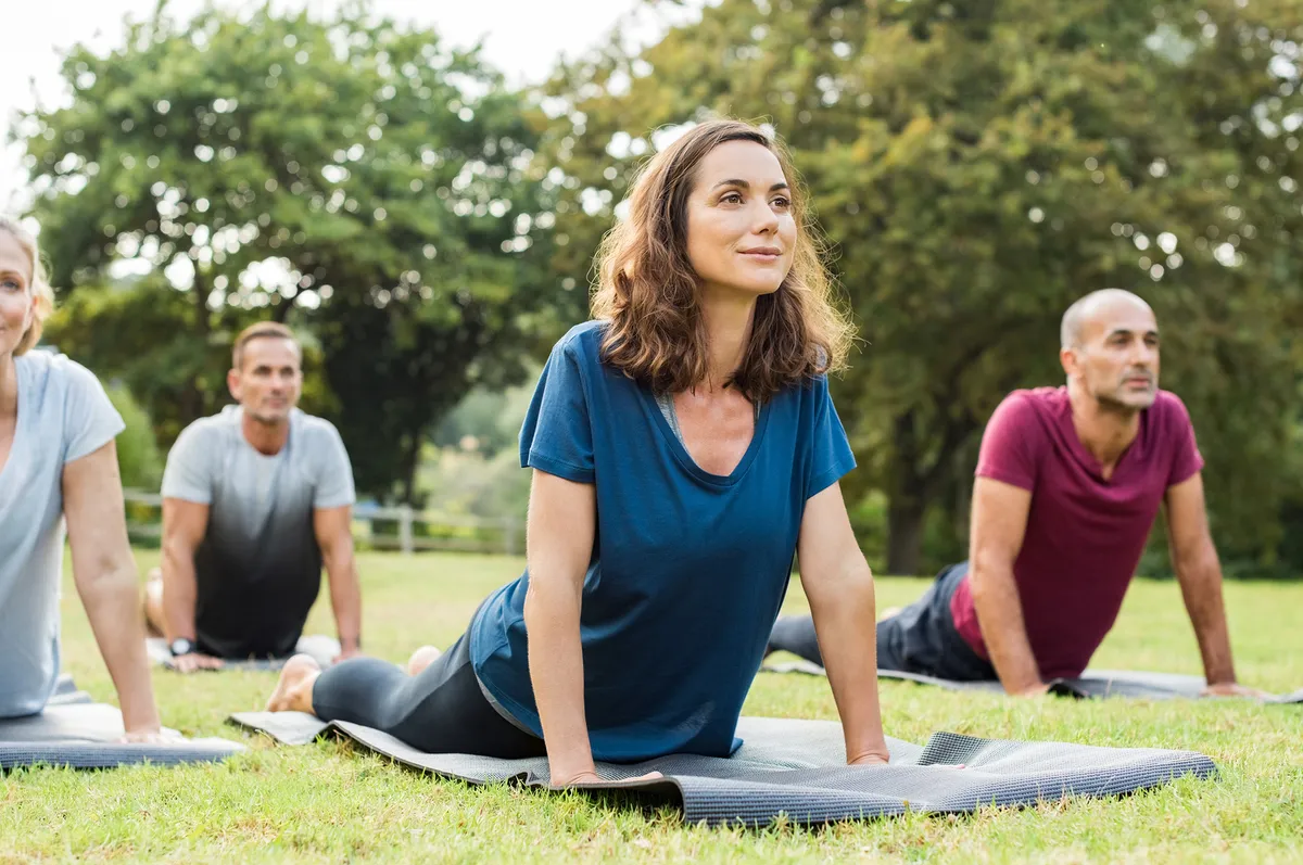 Grupo de personas practicando yoga al aire libre, una opción clave del tratamiento integral para la ansiedad que regula el cuerpo y la mente.