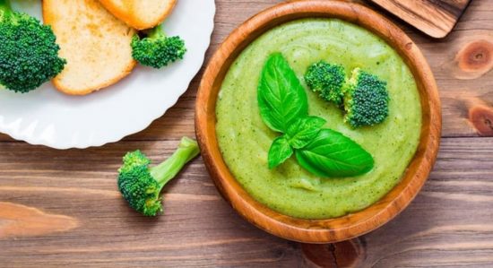 Hummus de brocoli: receta casera y saludable. Crema de brócoli servida en un tazón de madera con hojas de albahaca.