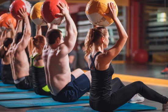 Entrenamiento funcional con balones medicinales Grupo de personas realizando ejercicios con balones medicinales en una clase de entrenamiento funcional.