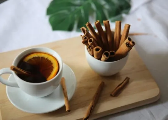 Té Verde: Propiedades de un Aliado Saludable. Taza de té caliente con canela y naranja, representando los beneficios y propiedades del té verde.