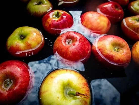 Varias manzanas rojas frescas flotando en agua, representando su poder de limpieza natural para la salud del colon.