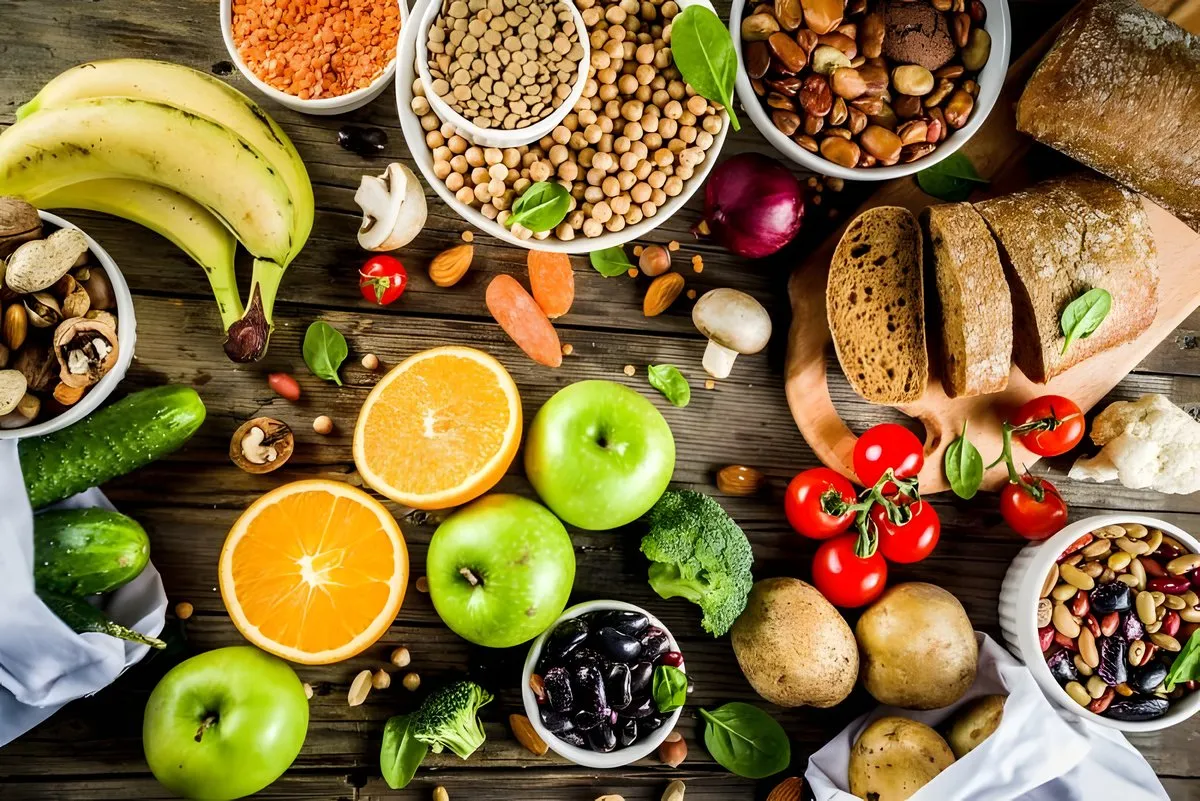 Frutas, verduras, legumbres y frutos secos variados sobre una mesa de madera.