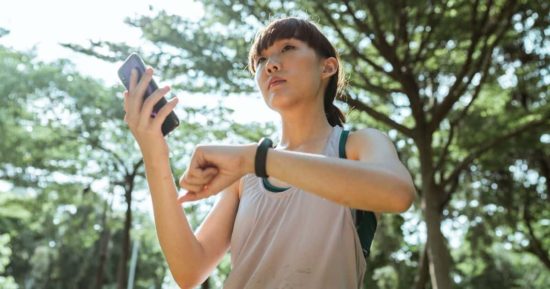 Las aplicaciones suelen funcionar en los smartwatch y celulares, para cuidar su salud todo el día mujer usando una aplicación con su teléfono y smartwatch para cuidar su salud