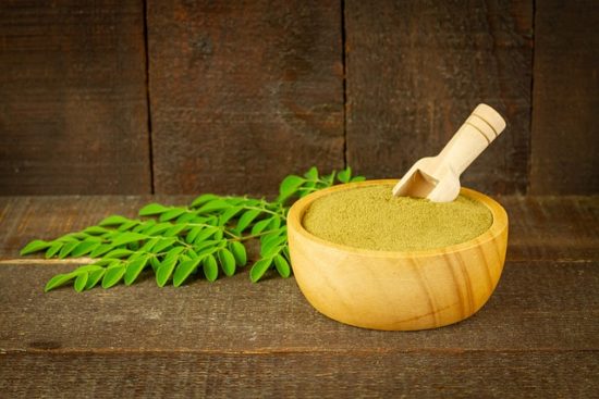 Polvo de moringa en un tazón de madera, usado como suplemento natural para bajar de peso.