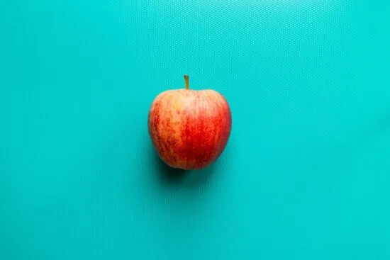 Una manzana roja y fresca sobre un fondo turquesa, simbolizando los beneficios de esta fruta para la salud del colon.