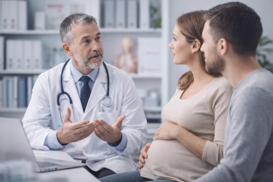 Células madre del cordón umbilical: guía completa para familias 9 Médico explicando información sobre células madre a mujer embarazada y su pareja en consultorio