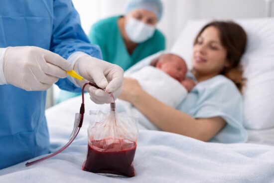 Profesional de salud recolectando sangre del cordón umbilical tras el nacimiento mientras madre sostiene a su bebé